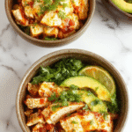 Colorful chicken burrito bowls plated with seasoned grilled chicken, fresh diced tomatoes, black beans, corn, and shredded cheese, garnished with cilantro on a rustic wooden table, vibrant and appetizing.